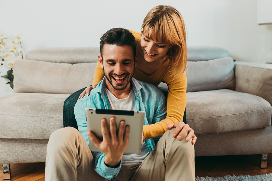 Client Center - Excited Young Couple Hanging Out in Their Living Room Using a Tablet